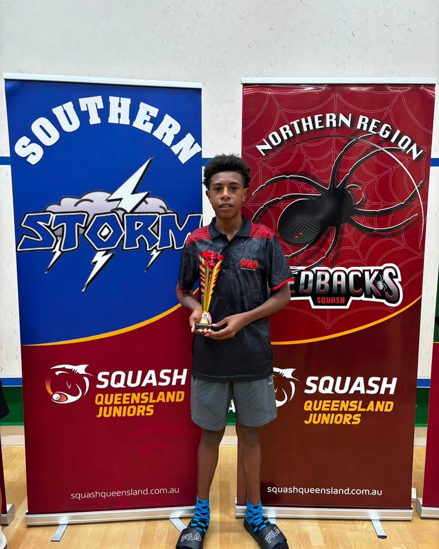 Joseph Yominao Jnr in Papua New Guinea team kit, holding a trophy at a Squash Queensland Juniors event